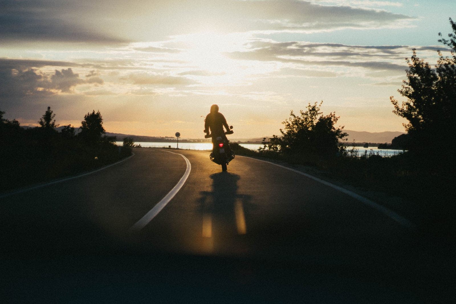 A motorcyclist riding an open highway at sunset