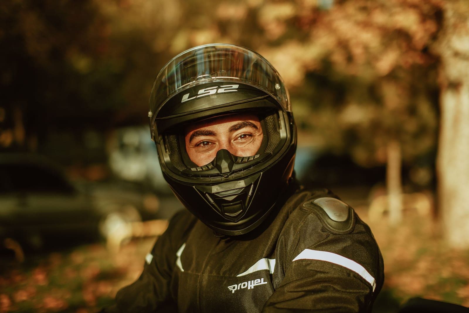 A new rider zipping up a riding jacket beside a motorcycle