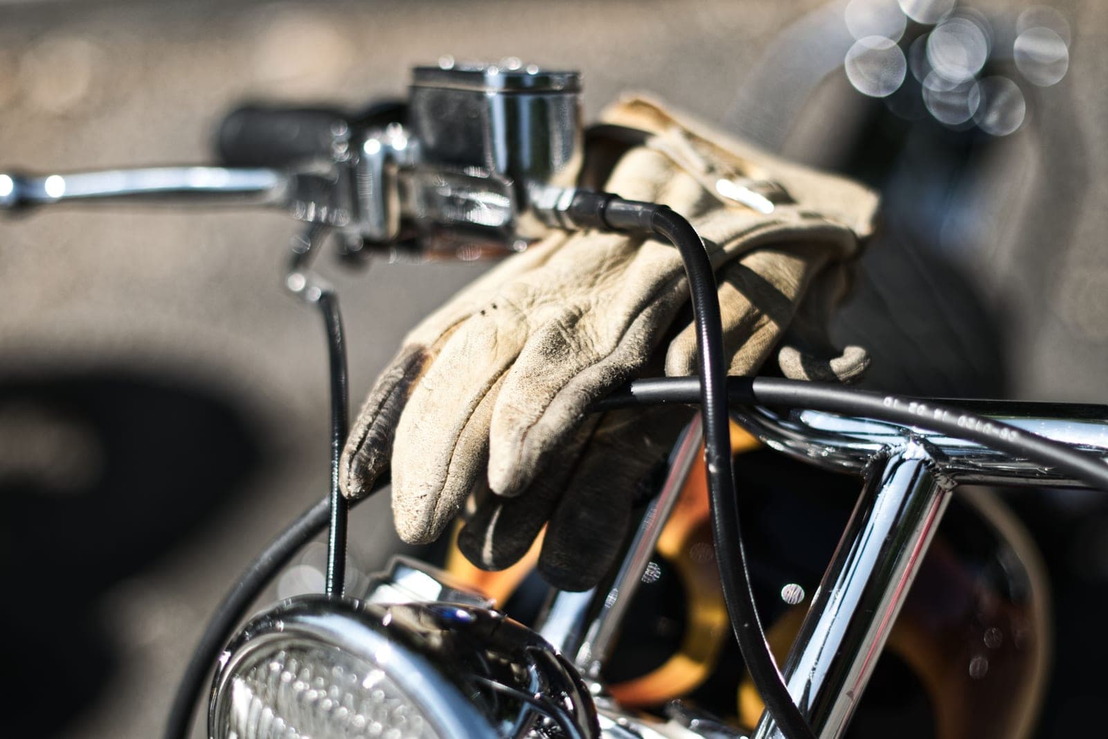 A rider's gloved hand on a handlebar control on the road